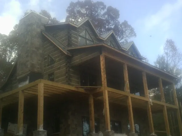 Stone chimney and dormers on a large log home with a timber porch in Buena