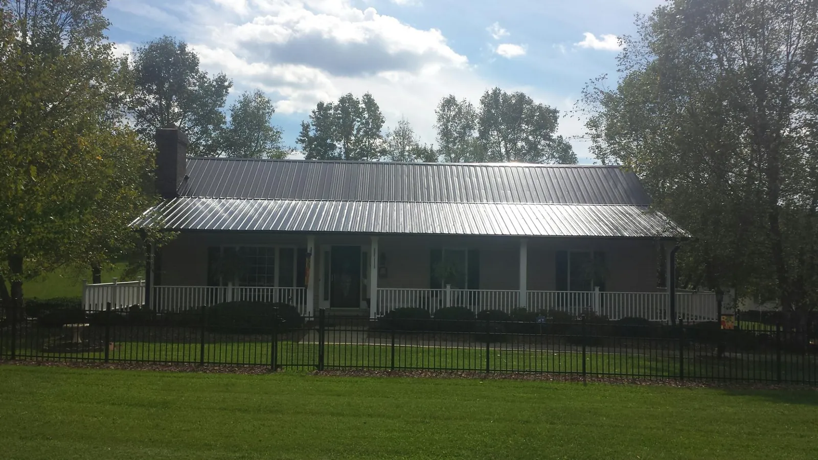 Gray metal roof on a brick ranch with a full width front porch — Gutter Guard Installation work by our crew in Buena