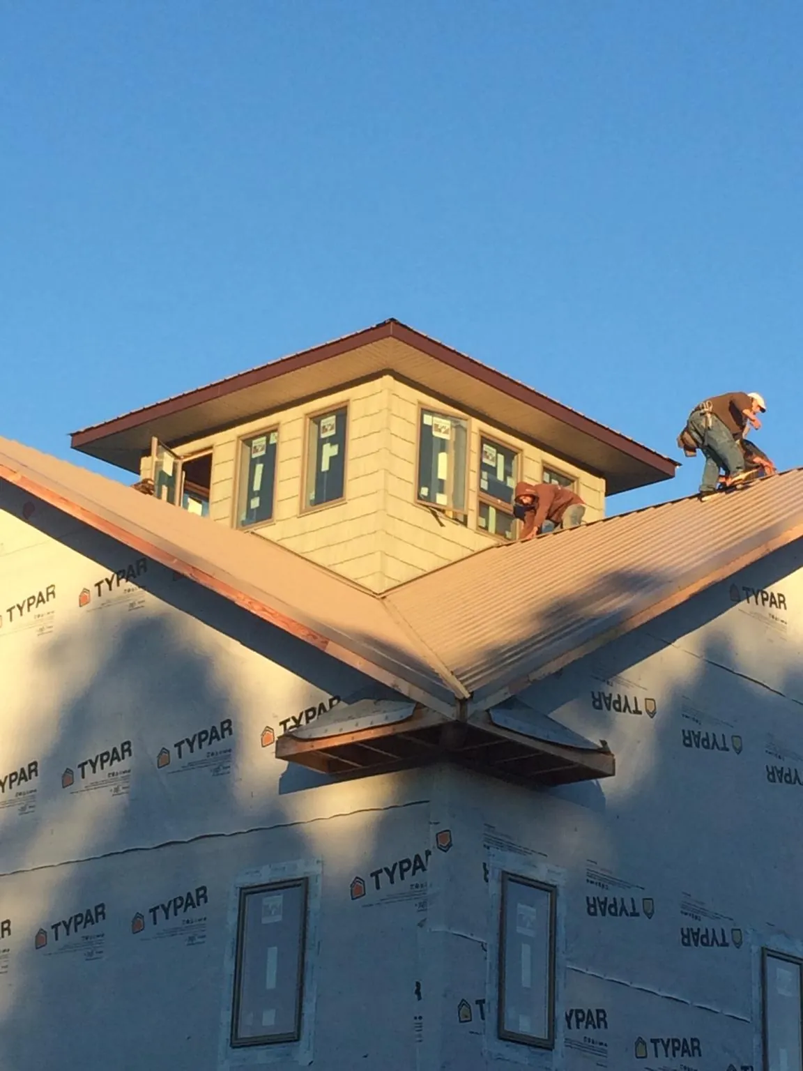 Roofers working around a rooftop cupola on a new metal roof at sunset — Roof Waterproofing in Buena by Roofing Brothers